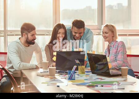 Designer gerne auf Laptop Bildschirm. Sind eine Gruppe von Freunden und Kollegen beobachten, lustige Videos während der Pausen bei der Arbeit. Stockfoto