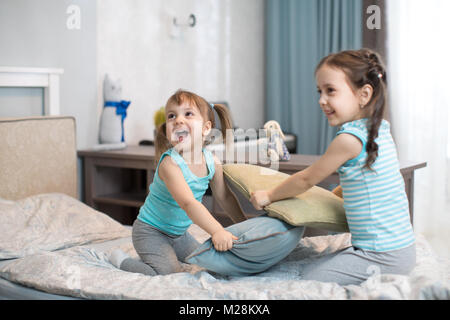 Kids Mädchen kämpfen mit Kissen im Schlafzimmer Stockfoto