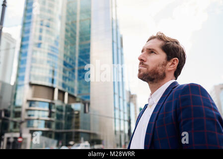 Ehrgeizige und erfolgreiche junge Unternehmer trägt einen Blazer tief in Gedanken, während allein in der Stadt stehend Stockfoto