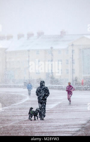 Llandudno, Wales, 6. Februar 2018. UK Wetter. Als eine gelbe Warnmeldung für Schnee für North Wales heute mit einigen Teilen von bis zu 8 cm auf höheren Boden vorhergesagt. Sehr ungewöhnlichen Schnee für die Seebad Llandudno im Norden von Wales als Menschen an der Strandpromenade © DGDImages/Alamy Leben Nachrichten entdeckt Stockfoto