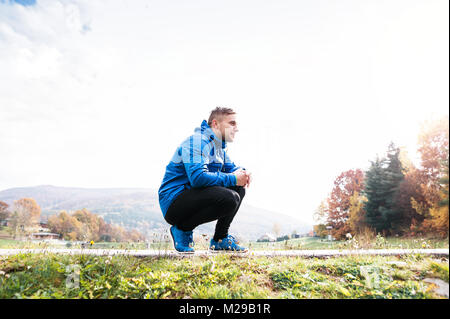Junger Läufer im Herbst Park ruht auf Asphalt weg. Stockfoto