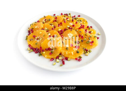 Orangensalat mit Pistazien und Granatäpfel an weiße Platte und auf weißem Hintergrund. Stockfoto