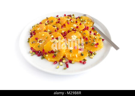 Orangensalat mit Granatäpfel und Pistazien auf weiße Platte und auf weißem Hintergrund. Stockfoto