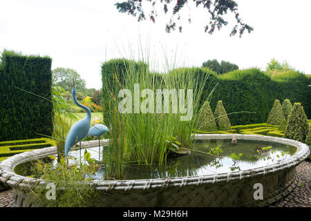 Heron Statuen in den Warenkorb Teich an Bourton Haus Garten, Bourton-on-the-Water, Moreton-in-Marsh, Gloucestershire, VEREINIGTES KÖNIGREICH Stockfoto