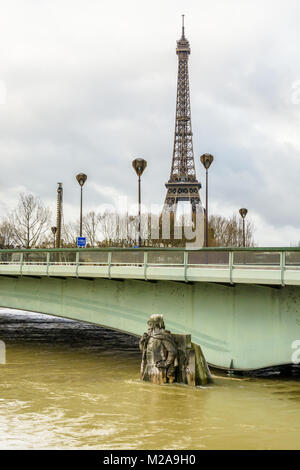 Das Alma-Brücke und die Hälfte getaucht Statue 'Le Zouave" während eines Winters Flut von der Seine und dem Eiffelturm in der Ferne unter einen bewölkten Himmel. Stockfoto