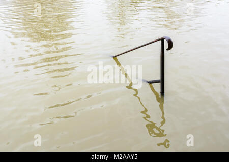 Der obere Teil von einem schmiedeeisernen Geländer klemmt aus dem schlammigen Fluten des geschwollenen Seine während eines Winters Flut Episode in Paris im Janu Stockfoto