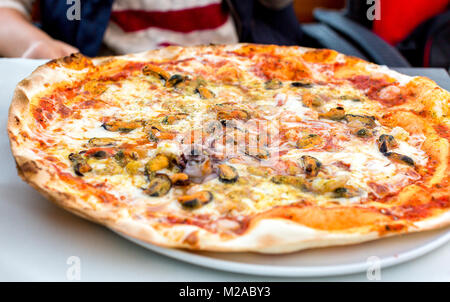 Appetitliche Pizza mit Meeresfrüchten auf einer Platte in einem Restaurant Stockfoto