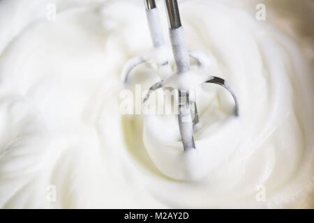 Mixer quirlen teilweise emersed in geschlagener Eischnee, der gerade geschlagen haben, bis sie steif sind, Stockfoto