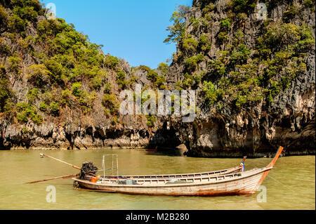 Der Strand am Ozean mit Blick auf zwei kleine Boote mit einer küstenlinie zwischen den Felsen mit tropischen Wald überwuchert. Sonnigen Tag. Stockfoto