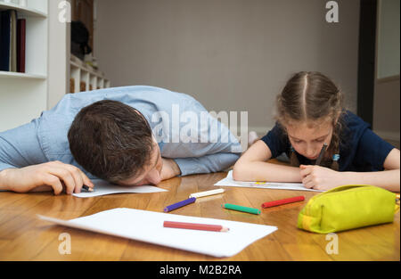 Kleines Mädchen Zeichnung auf dem Boden. Papa schlief ein. Stockfoto