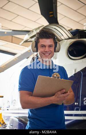 Portrait der männlichen Aero Ingenieur mit Zwischenablage Durchführung auf Helikopter im Hangar prüfen Stockfoto