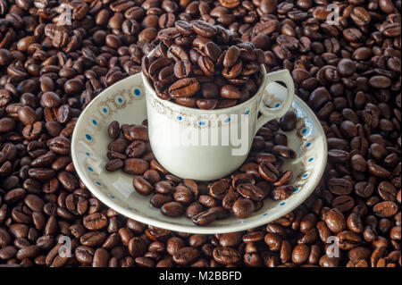 Tasse und Untertasse voller Kaffeebohnen auf einer Kaffeebohne Hintergrund espresso Konzept mit kopieren. Stockfoto