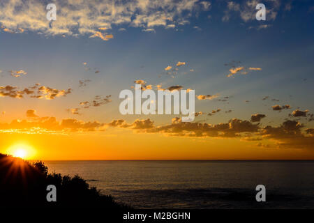 Golden epic glorreichen Südafrikanischen idyllische malerischen Sonnenuntergang an der Küste über dem Meer in der Nähe von Kapstadt Südafrika, Sonne, blauer Himmel, Wolken, ruhige See Stockfoto