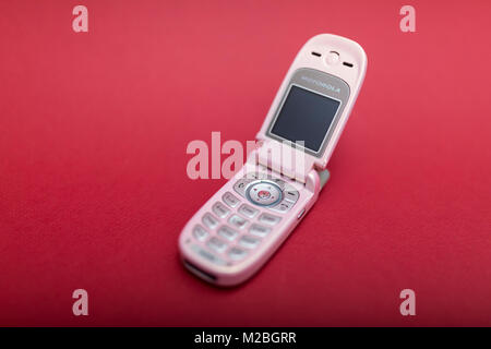 Cool und klassischen Motorola V220 Pink retro flip Zelle oder Handy vor einem roten Hintergrund isoliert Stockfoto