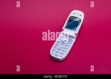 Cool und klassischen Motorola V220 Pink retro flip Zelle oder Handy vor einem roten Hintergrund isoliert Stockfoto