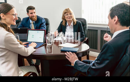 Zuversichtlich Geschäft Leute lächelnd, während sie ihren Kollegen eine erfolgreiche Plan während der Verwaltungsrat treffen in die Konferenz Stockfoto