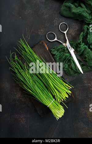 grüne Zwiebel an Bord und auf einem Tisch Stockfoto