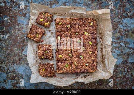 Hausgemachte Saatgut, Mutter, getrocknete Früchte und dunkle Schokolade Oat Energieriegel auf Backpapier auf schiefer Hintergrund Stockfoto