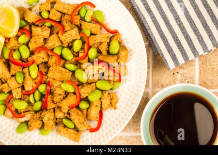 Frittierte chinesischen Stil vegetarische oder vegane Tofu mit würzigen roten Chilis und Edamame Bohnen auf eine geflieste Küche Tabelle Stockfoto