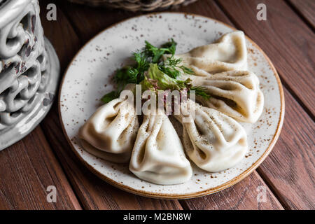 Georgische Knödel Khinkali mit Fleisch, Grünen auf einer hölzernen rustikalen Tisch Stockfoto