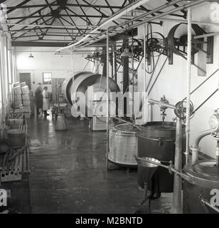 Historisches Bild der 1950er Jahre des Innenraums einer industriellen Molkerei in Irland, das die Milchverarbeitungsgeräte zeigt, einschließlich der großen Fässer, die die Milch zu Butter abpumpen. Es wird geschätzt, dass es etwa 20 Liter Milch braucht, um ein Kilogramm Butter zu produzieren. Irland ist weltberühmt für seine Milchprodukte. Stockfoto