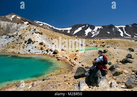 Neuseeland, Nordinsel, Whakapapa, Tongariro National Park, Blick auf Emerald Lakes. Frau ruht während des Trekking. Unesco-Weltkulturerbe. Stockfoto