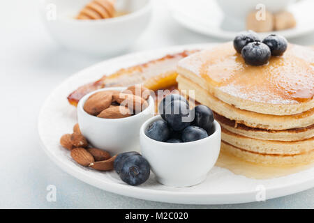 Ein Stapel von leckeren Pfannkuchen mit Honig, Kaffee und Heidelbeeren auf einem hellblauen Hintergrund. Tolles Frühstück für den Valentinstag Stockfoto