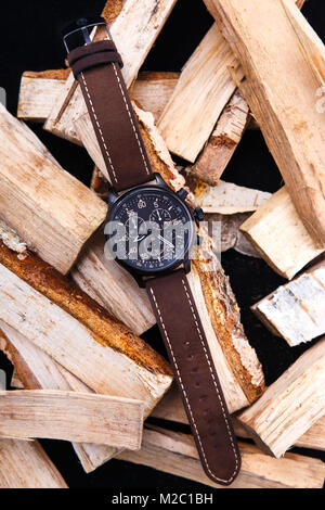 Watch mens braun Lederband auf Holz. Schwarzes Zifferblatt. Messer mit orangefarbenen Ziehgriff Stockfoto
