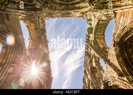 Zu Sonnenlicht durch Torbögen von Whitby Abbey, Whitby, Yorkshire, UK peaking Stockfoto