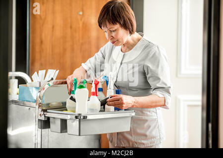 Senior Zimmermädchen mit maid Warenkorb in den Hotelflur Stockfoto