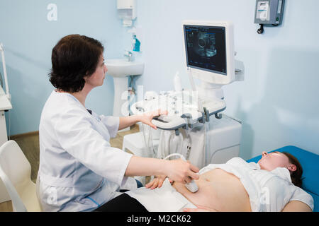 Schwangere Frau, die Ultraschallbehandlung im Krankenhaus Stockfoto