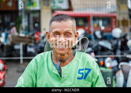 Glück: fröhlich, freundliche lokale kambodschanische Cyclo City Tour Zyklus Rikscha Fahrer mit den schlechten Zähnen in einem grünen Shirt in Phnom Penh, der Hauptstadt von Kambodscha Stockfoto