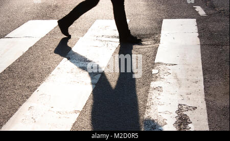 Stadt Zebrastreifen mit zwei verschwommen zu Fuß Fußgänger, lange Schatten in Schwarz und Weiß mit hohem Kontrast Stockfoto