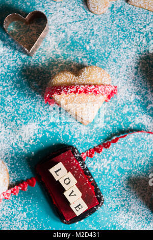 Backen Herzförmige Plätzchen zum Valentinstag, mit den Worten der Liebe mit farbigen Stempel erstellt, über einen azul Hintergrund, Ansicht von oben Stockfoto