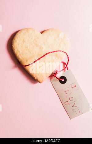 Schöne herzförmige Plätzchen für den Valentinstag mit einem Gruß' s Karte mit "I love U"-Nachricht über einen rosa Hintergrund, Ansicht von oben. Stockfoto