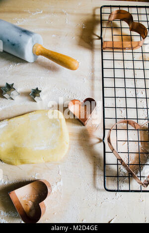 Backen Herzförmige Plätzchen zum Valentinstag, über eine Holz- Hintergrund, mit Cookie Cutter mit Herzform Top View Stockfoto