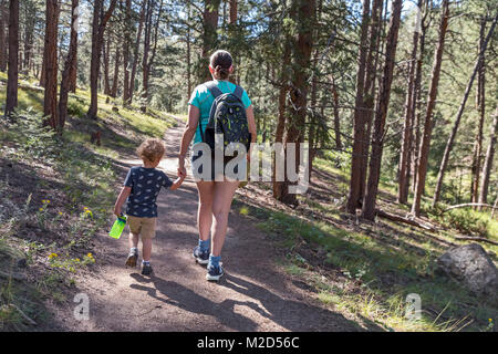 Kittredge, Colorado - ein 3-jähriger Junge trägt eine Wasserflasche wie Wanderungen mit seiner Mutter auf dem Panorama Point Trail. Stockfoto