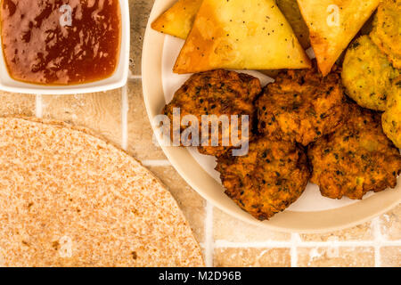 Indisches essen Snacks vegetarische Tikka vegetarische Samosa Zwiebel Bhaji mit chapatis Fladenbrot auf eine geflieste Küche Tisch Stockfoto