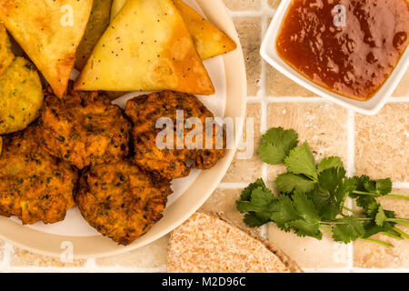 Indisches essen Snacks vegetarische Tikka vegetarische Samosa Zwiebel Bhaji mit chapatis Fladenbrot auf eine geflieste Küche Tisch Stockfoto