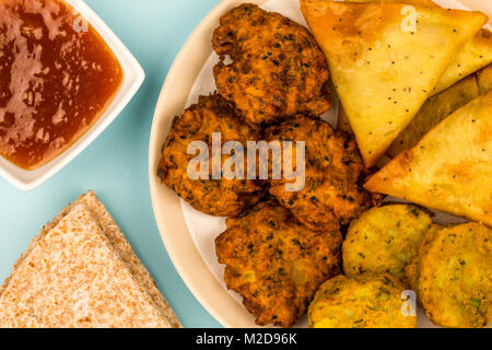 Indisches essen Snacks vegetarische Tikka vegetarische Samosa Zwiebel Bhaji mit chapatis Fladenbrot gegen einen hellblauen Hintergrund Stockfoto