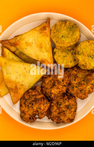 Indisches essen Snacks vegetarische Tikka vegetarische Samosa Zwiebel Bhaji gegen einen orangen Hintergrund Stockfoto