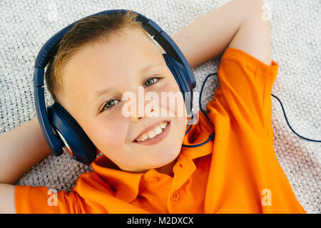 Lächelnd Kaukasischen jungen Verlegung auf Decke im Park zu hören kopfhörer Stockfoto
