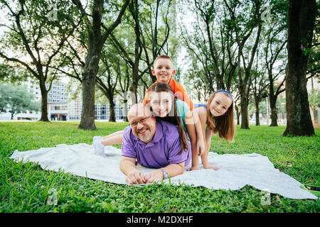 Portrait der kaukasischen Jungen und Mädchen Festlegung auf der Rückseite des Vaters im Park Stockfoto