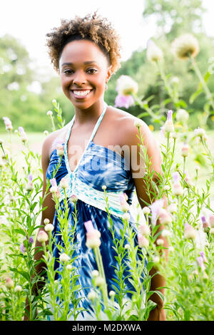 Portrait von lächelnden Frau, die in gemischten Rennen Wildblumen Stockfoto