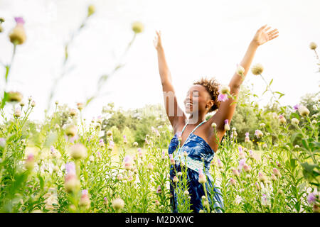 Lächelnd gemischten Rasse Frau Feiern im Bereich der Wildblumen Stockfoto