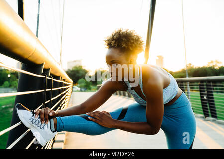 Gemischte Rasse Frau stretching Bein auf der Brücke Geländer Stockfoto