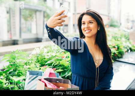 Hispanic Frau sitzt auf der Bank posiert für Handy selfie Stockfoto
