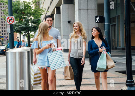 Freunde zu Fuß in die Stadt, Shopping Taschen sms auf Handys Stockfoto