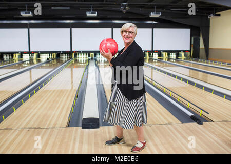 Portrait der kaukasischen Frau mit Bowling Ball in der Nähe Lane Stockfoto