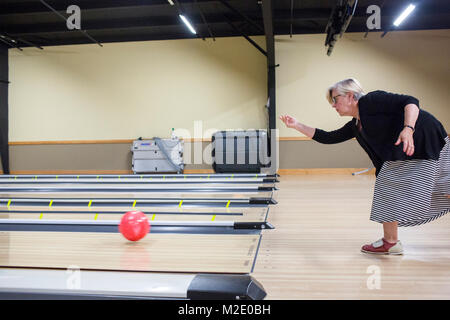 Kaukasische Frau loslassen Bowling Ball in der Spur Stockfoto